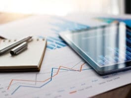 Business Document Report On Paper And Tablet With Sales Data And Financial Business Growth Graph On Table Background.