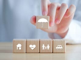 Insurance Concept. Protection Against A Possible Eventuality. Hand Holding Umbrella Icon And House, Car, Family And Health Icon On Wooden Block For Assurance Life Concept.