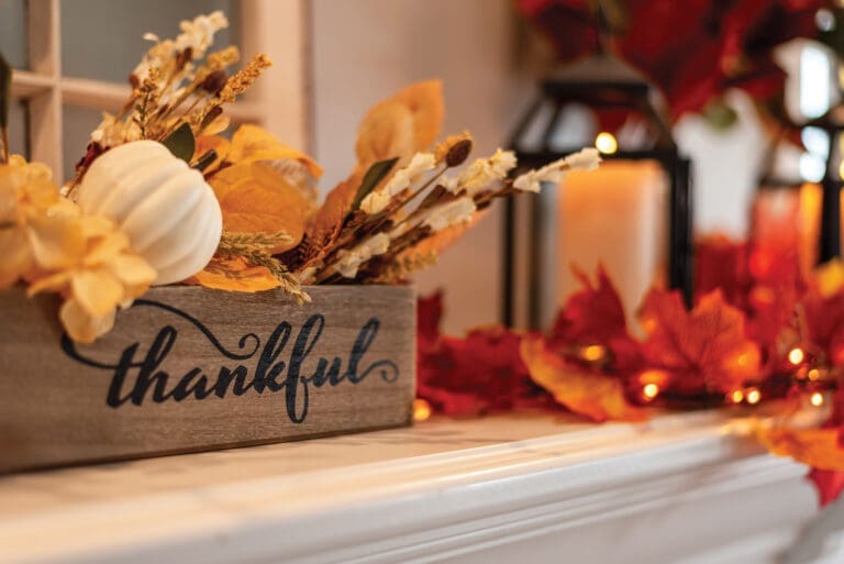 Fall Holiday Mantel Decorated With Colorful Leaves And Twinkle Lights