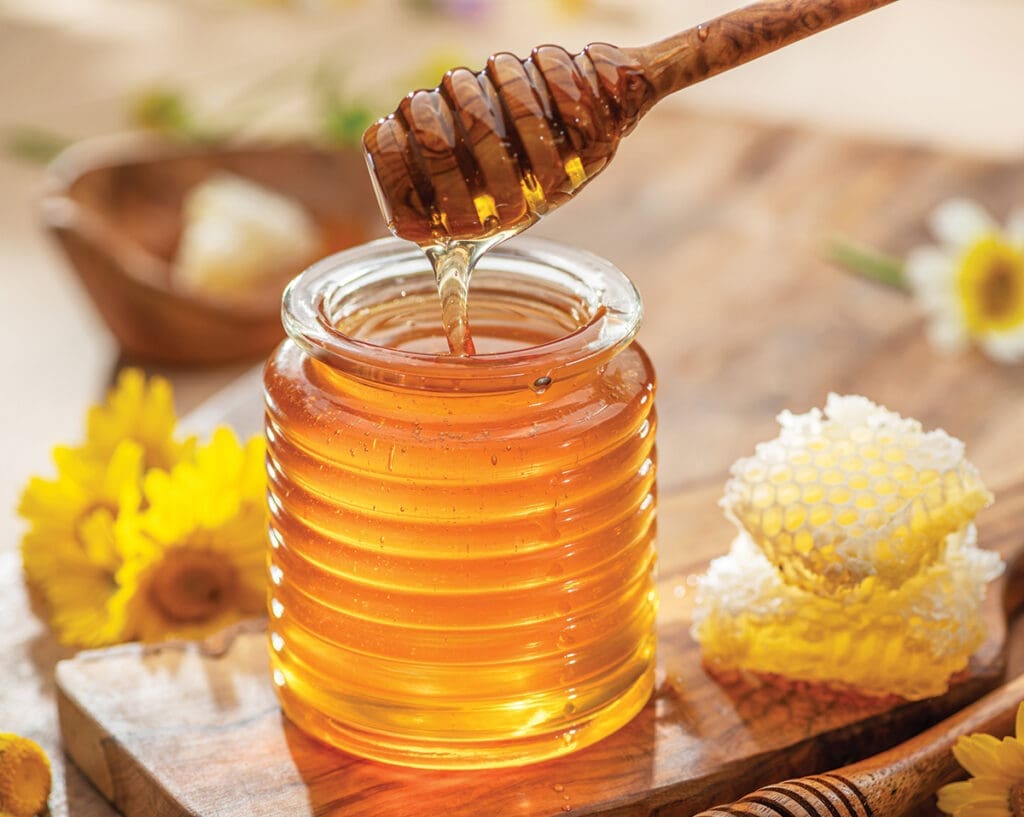 Natural Organic Honey In Glass Jar, Honey Dipper And Honeycombs Are Near. Natural Food Background.